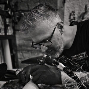 Photo en noir et blanc d'un tatoueur